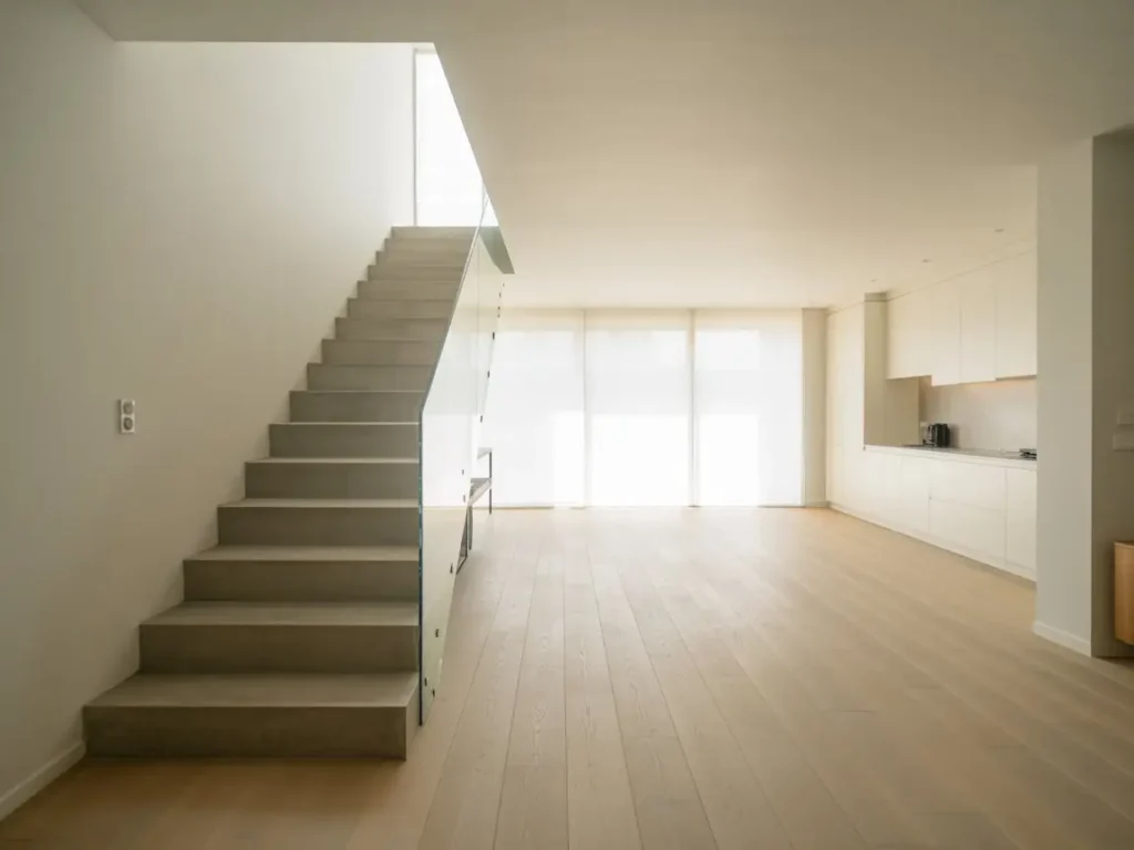 escalera moderna junto a salón comedor reformado con pladur y cocina integrada luminosa